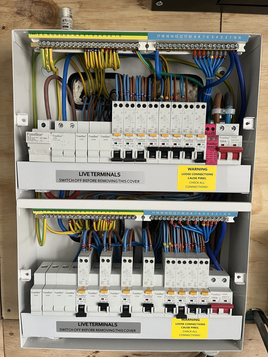 Two new consumer units mounted one above the other, with neatly dressed wiring and labelled circuit breakers